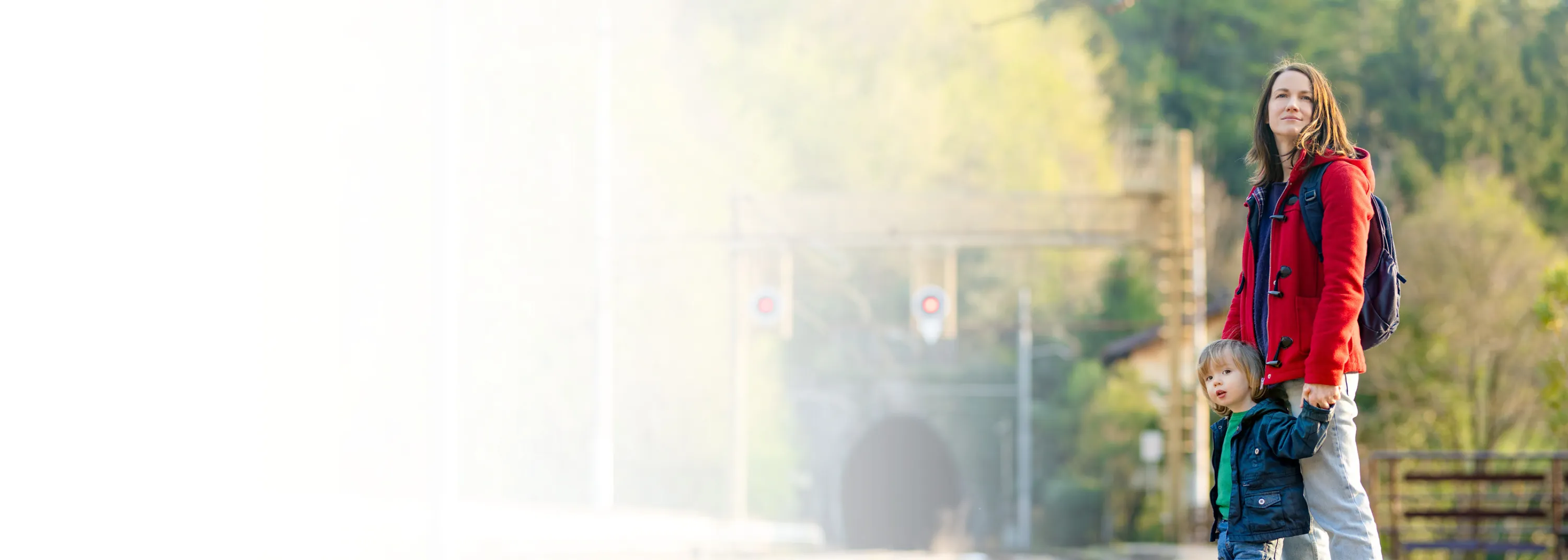 Eine Frau steht mit ihrem Sohn am Bahnsteig und wartet auf den Zug